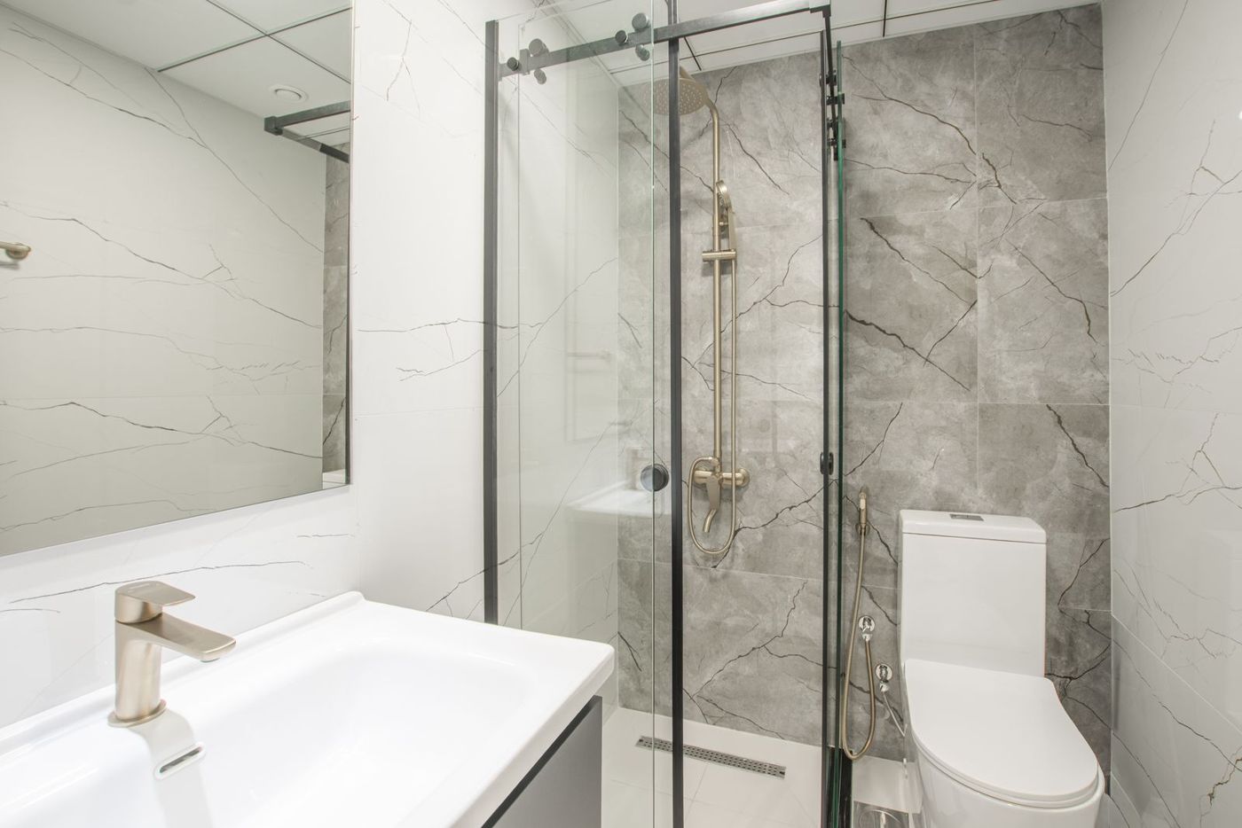 A modern walk-in shower with a glass panel beside a white sink